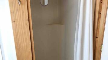 Un espace de douche doté d’un cadre de porte en bois, d’un rideau de douche et d’un miroir rond.