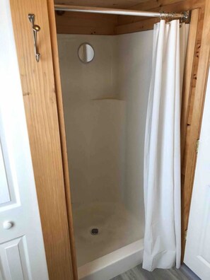 A shower enclosure with a wooden door frame, a shower curtain, and a circular mirror. - Mallets Bay|Lake Front|Dog Friendly|Private Beach (Colchester)