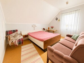 A bedroom with a bed, a chair, a table, and a window with curtains. - Midnight Sun House in Eggum, Lofoten (Vestvågøy)