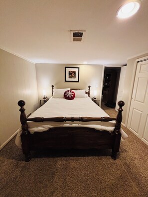 A bedroom with a large bed, a ceiling light, a framed picture on the wall, and a door to the right. - Basement Apartment w/i walking distance to UNC! (Greeley)