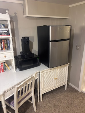 A compact kitchenette with a white countertop, a black coffee maker, a stainless steel refrigerator, and a white cabinet with books. - Basement Apartment w/i walking distance to UNC! (Greeley)