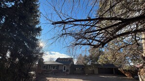 A residential property with a gravel driveway, a detached garage, and a house with a sloped roof.