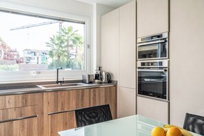 Een moderne keuken met een inbouwoven, een koffiezetapparaat en een raam met uitzicht op een woonwijk.