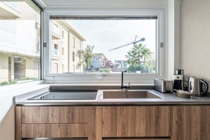 Eine moderne Küche mit großem Fenster, integriertem Spülbecken und Kaffeemaschine auf der Arbeitsplatte.