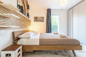 Quarto moderno com cama de madeira, mesa de cabeceira, prateleira na parede e janela com cortinas.