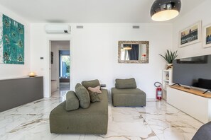 A modern living room with a sofa set, a television, and artwork on the walls. - Oasi del Garda in Desenzano - Pool&Garden&Garage (Desenzano del Garda)