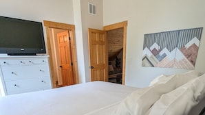 A bedroom with a bed, a television on a stand, and a painting on the wall. - Harrier Pine Chalet At The Running Y (Klamath Falls)