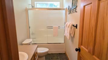 Een badkamer met douche, toilet en wastafel.