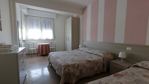 A bedroom with two beds, a desk, a chair, a table, and a window with curtains. - Rosa Apartment – Three-Room Lake View with Wi-Fi, Air Conditioning, and Lake View (Sirmione)