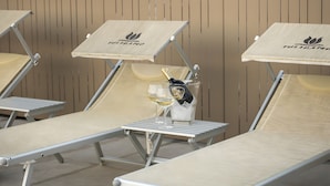 A row of sun loungers with a branded umbrella, a bottle of champagne, and a glass of white wine.