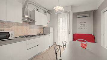 A modern kitchen with white cabinets, a gas stove, a microwave, and a ventilation hood.
