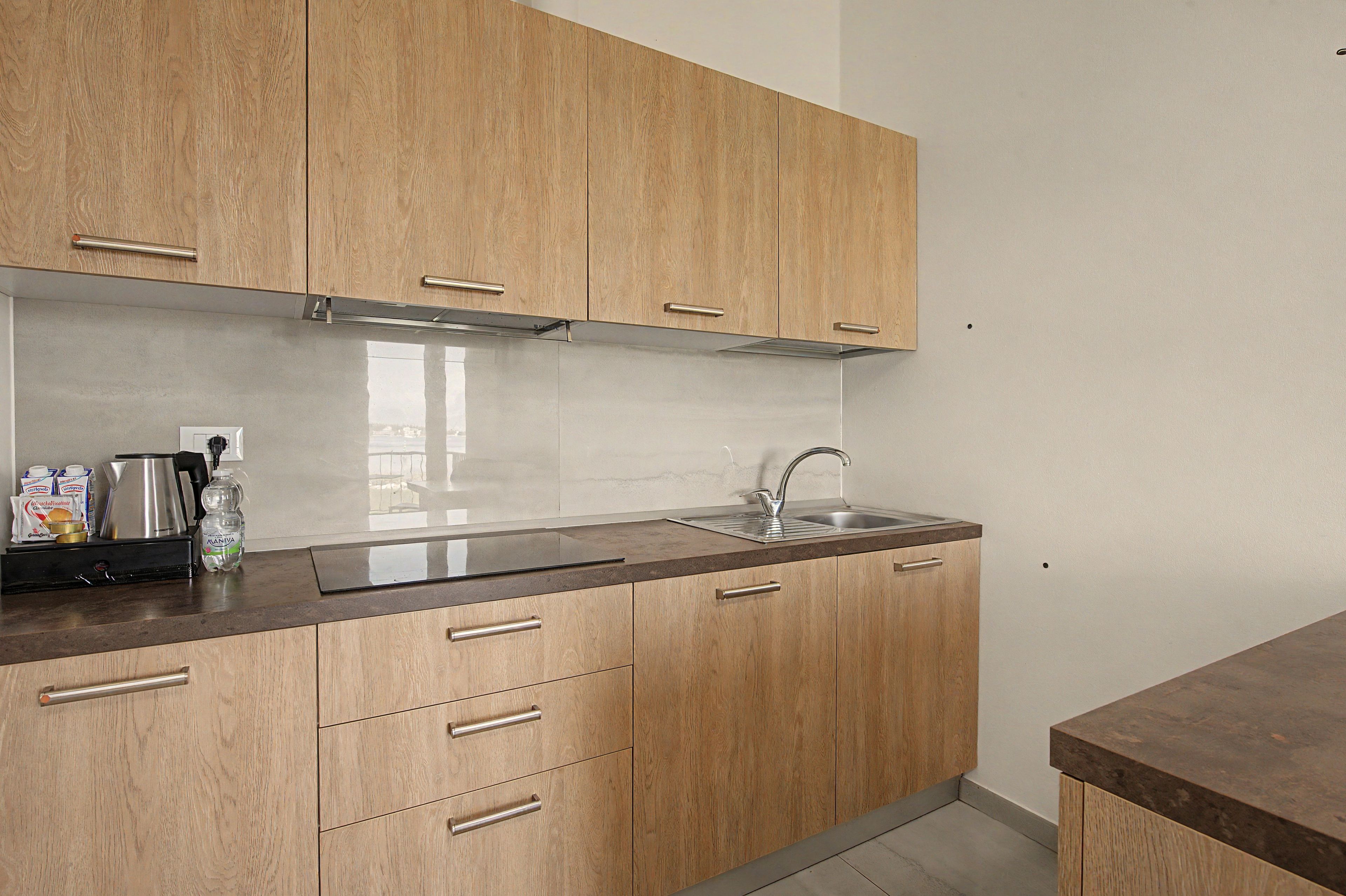 A kitchen with wooden cabinets, a stainless steel sink, and a countertop with various items.