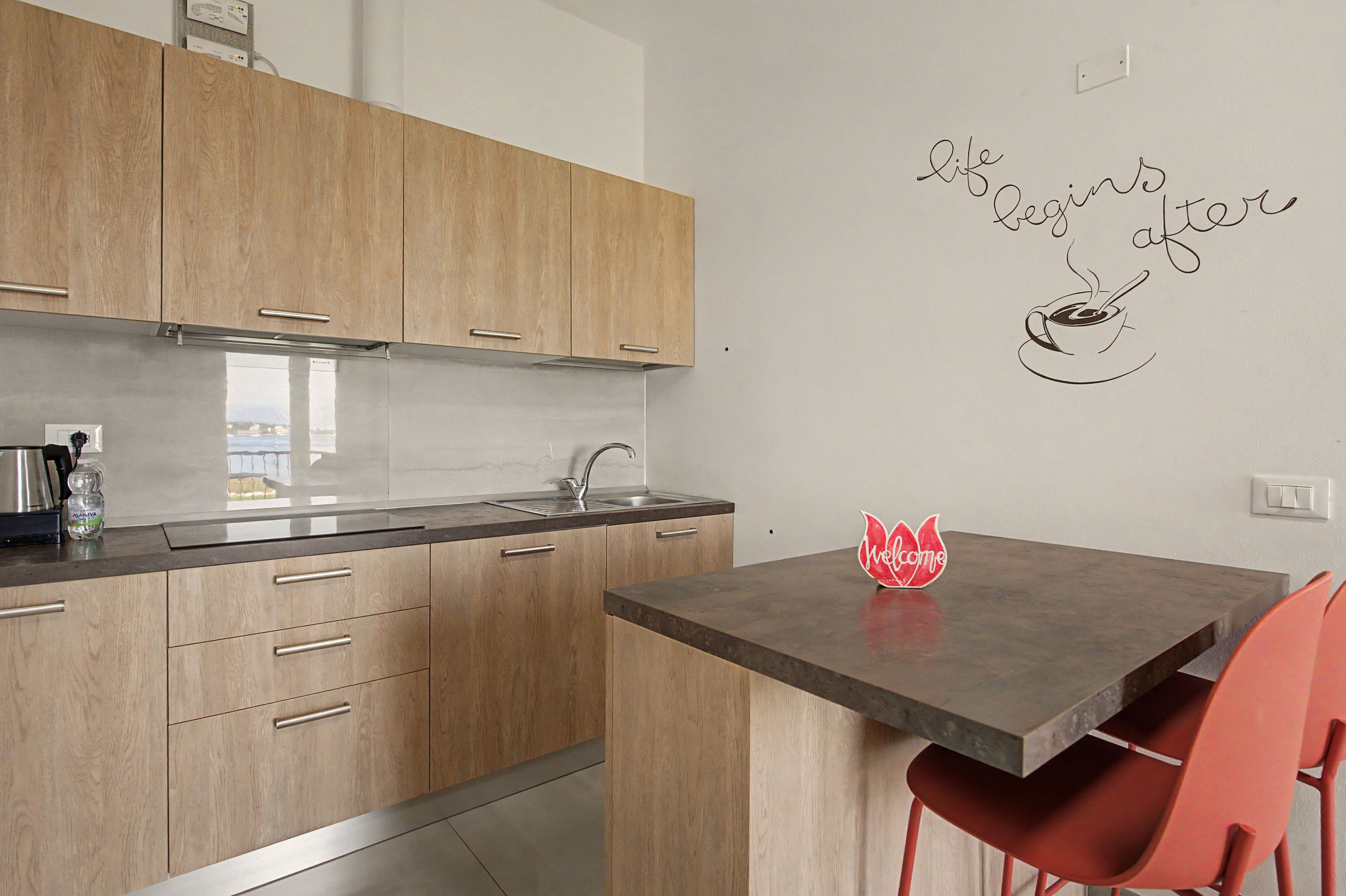 Eine moderne Küche mit Holzausstattung, einer Edelstahlspüle und einer Wanddekoration mit einer Kaffeetasse und der Aufschrift 'life begins after coffee'.