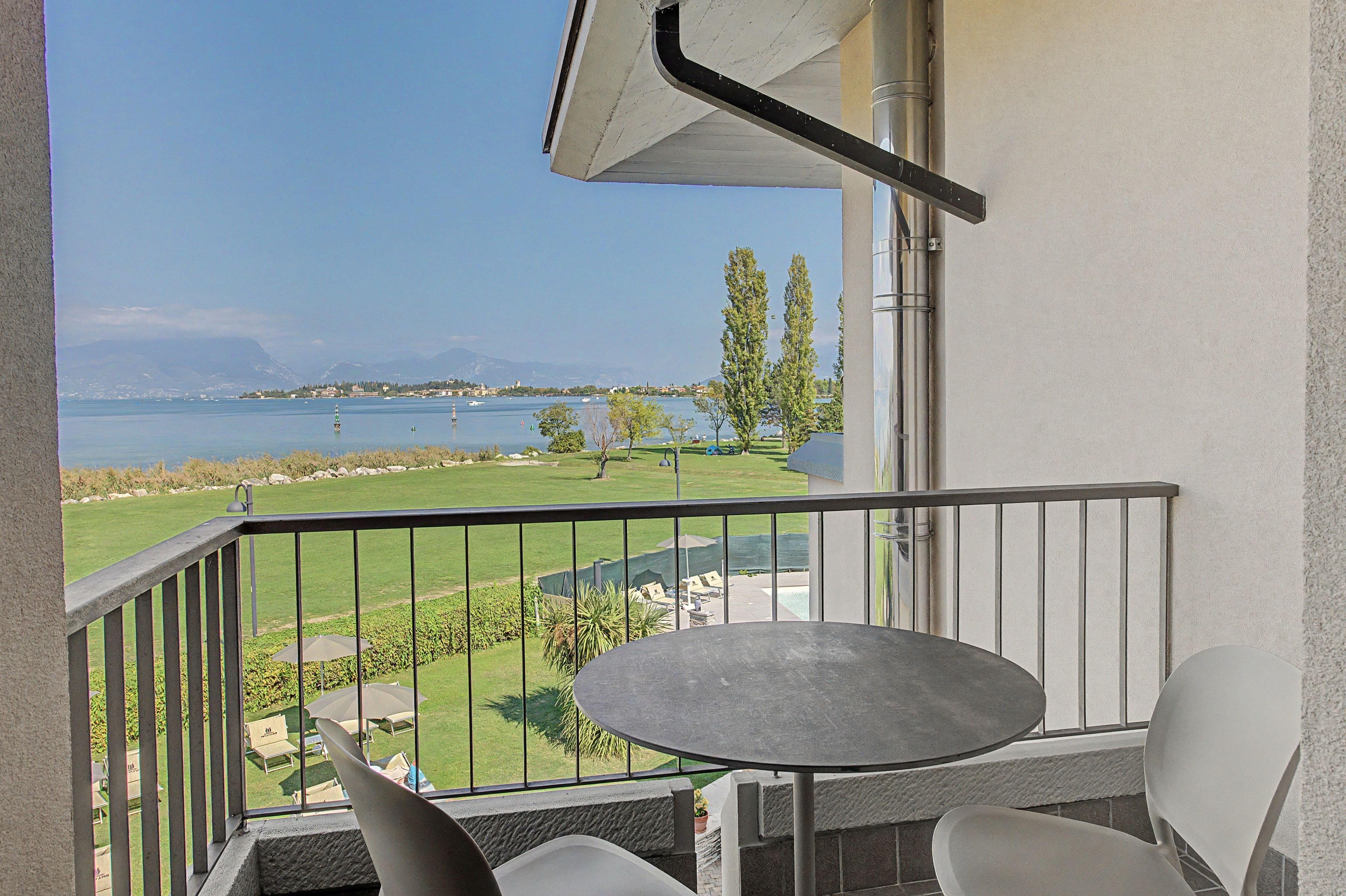 Ein Balkon mit Blick auf einen See, eine Wiese und ein Berg in der Ferne.