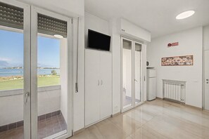 A modern interior with a balcony, a flat-screen TV, and a radiator. - Margherita - Open Space Lake View Apartment with Lake View, Wi-Fi, and Air Conditioning (Sirmione)