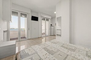 Une chambre d’hôtel équipée d’un lit, d’une télévision, d’un réfrigérateur et offrant une vue sur la mer.