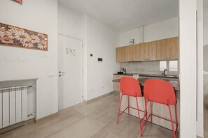 Eine moderne Küche mit zwei roten Barhocker, einem Holzkasten und einer Heizung.