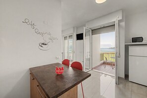 Une cuisine moderne avec un coin repas, une vue sur la mer et un objet décoratif rouge posé sur la table.