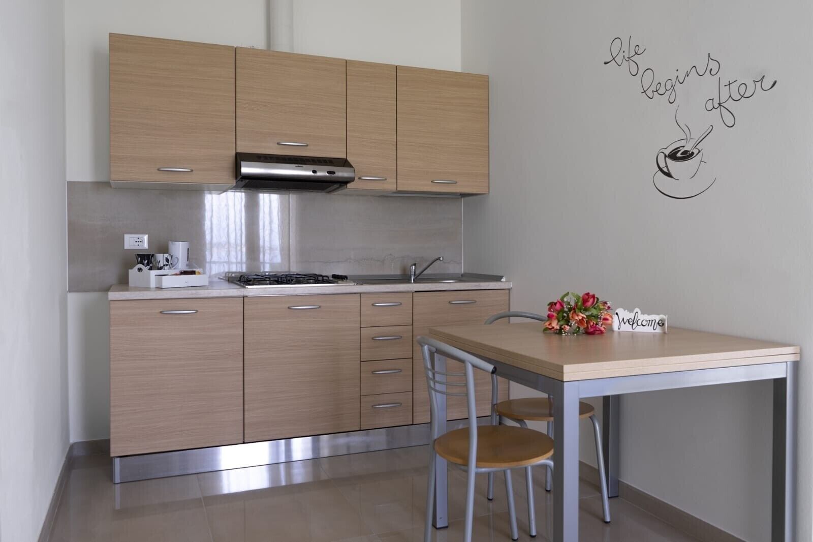 Una cocina moderna con armarios de madera, extractor de acero inoxidable y un comedor con mesa y sillas.