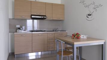 Una cocina moderna con armarios de madera, extractor de acero inoxidable y un comedor con mesa y sillas.