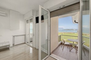Ein modernes Interieur mit einer Schiebetür, die auf einen Balkon mit Blick auf ein Gewässer und Berge führt.