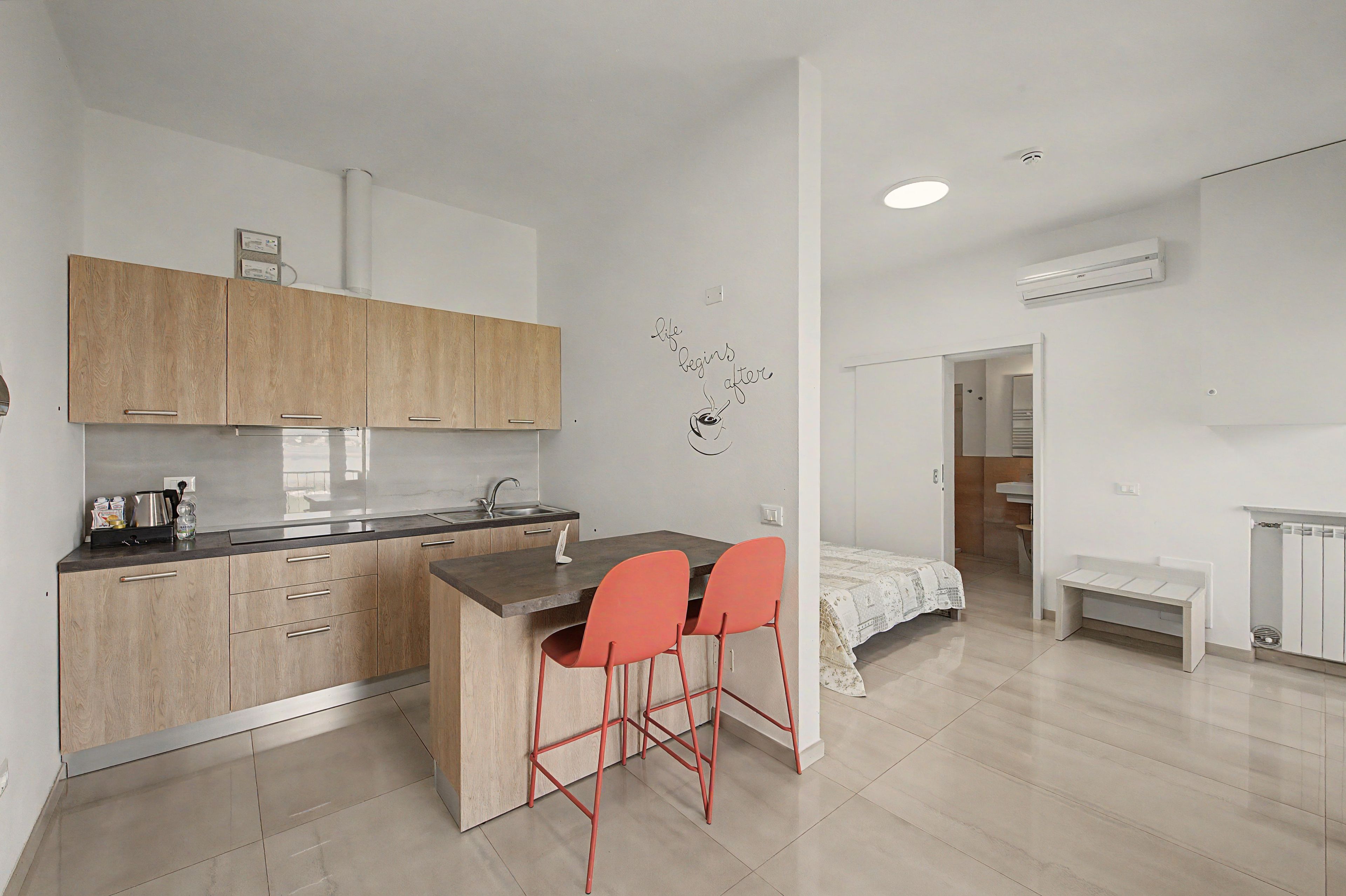 A modern kitchen with wooden cabinets, a central island, and red bar stools.