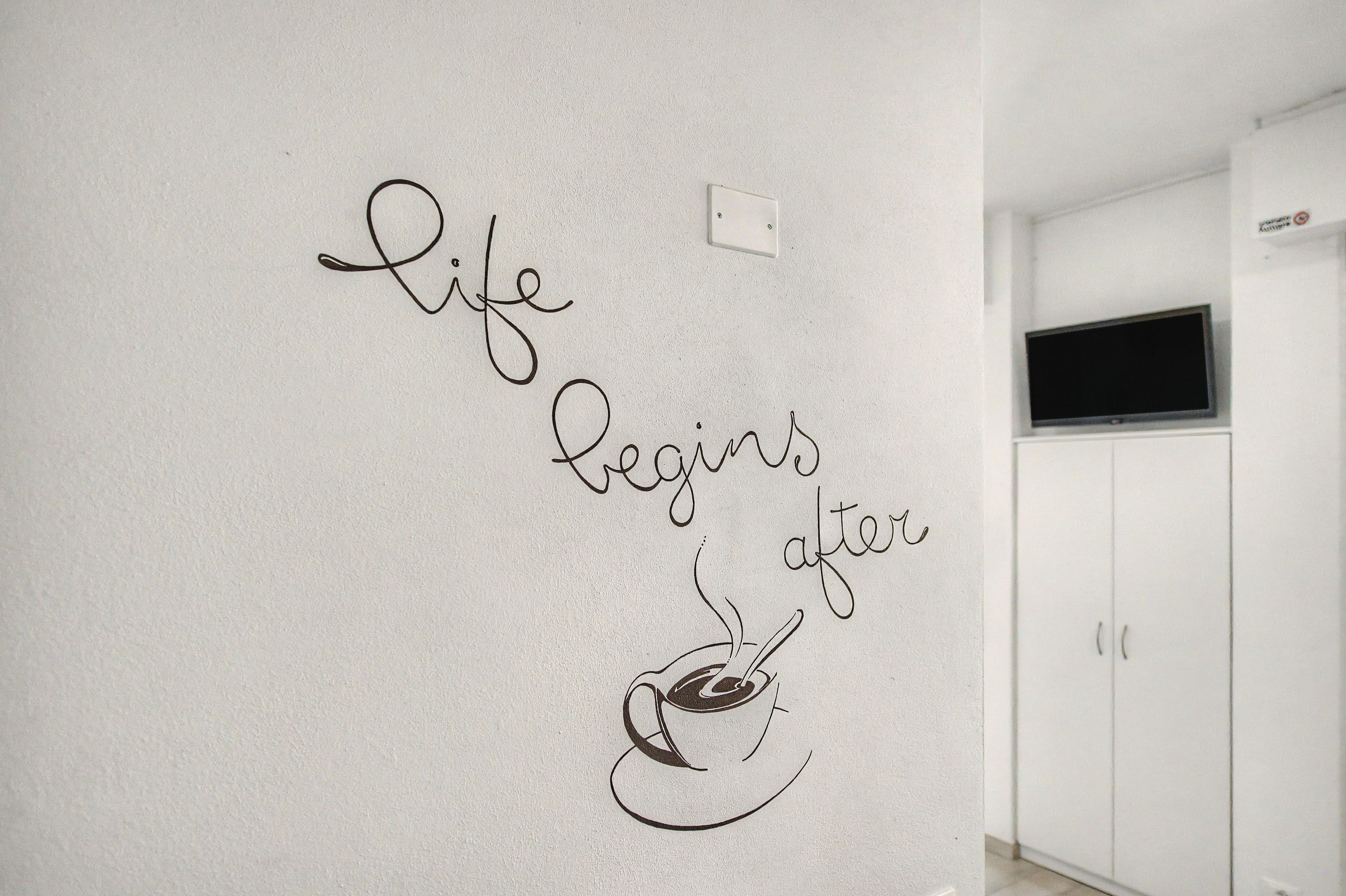 Un muro con una citazione motivazionale e un'illustrazione di una tazza da caffè.