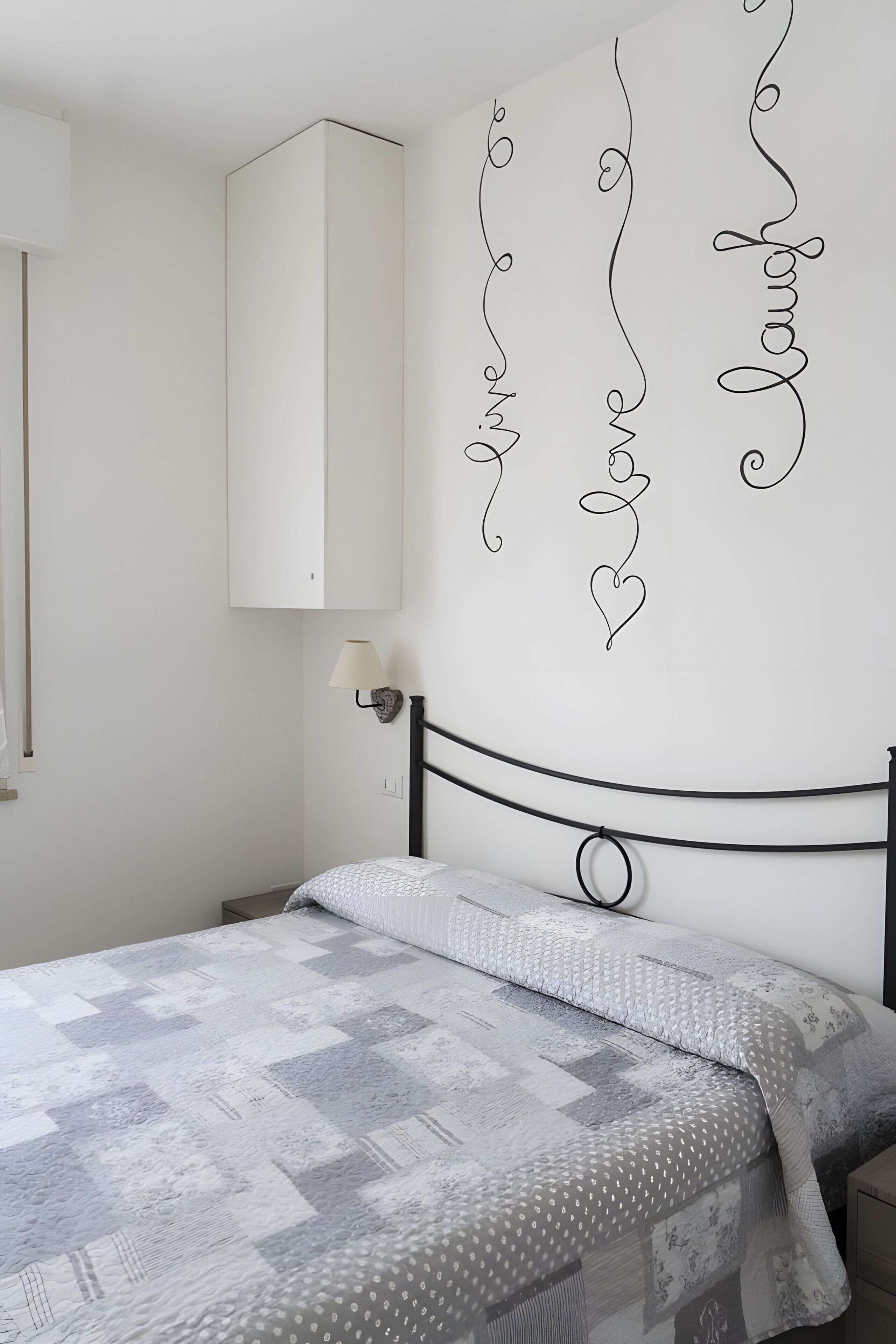 Une chambre à coucher comprenant un lit, une lampe fixée au mur et un élément décoratif mural.