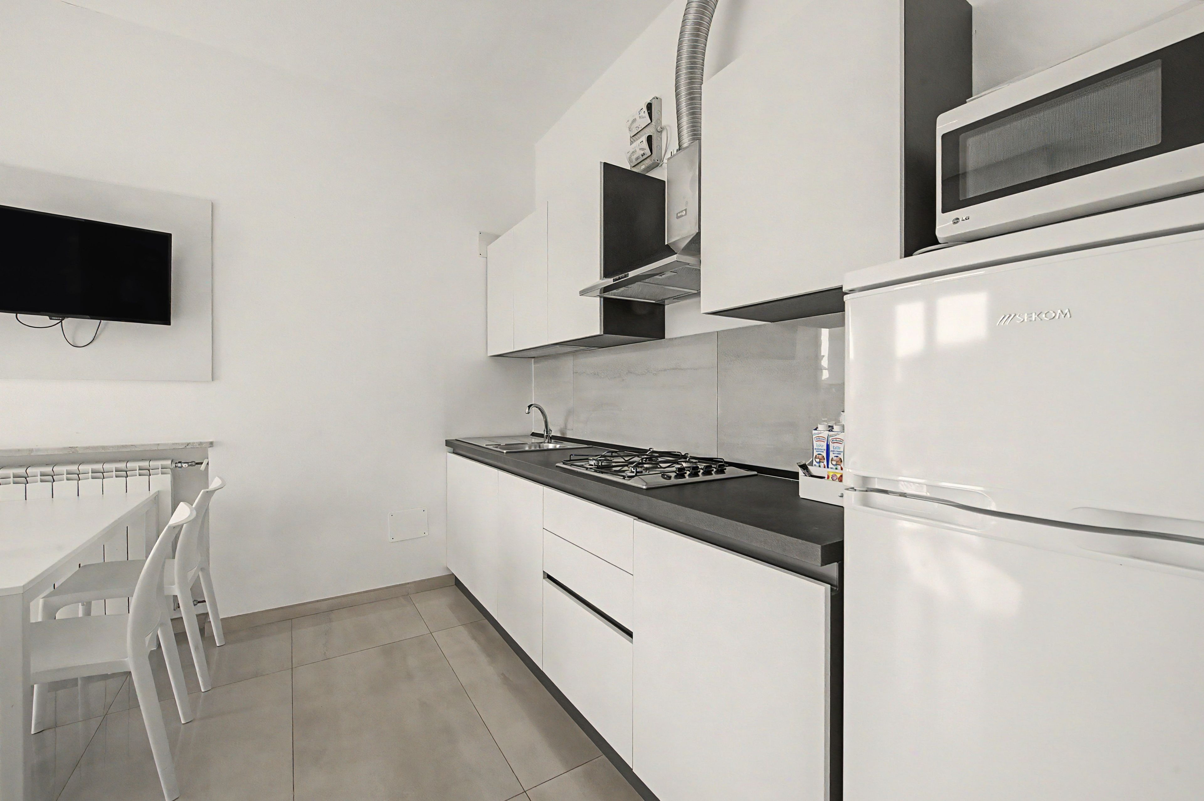 A modern kitchen with white cabinetry, a built-in microwave, a gas stove, and a refrigerator.