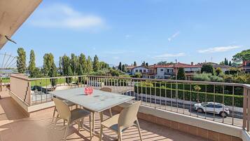 A balcony with a table and chairs, overlooking a residential area with houses and a road.