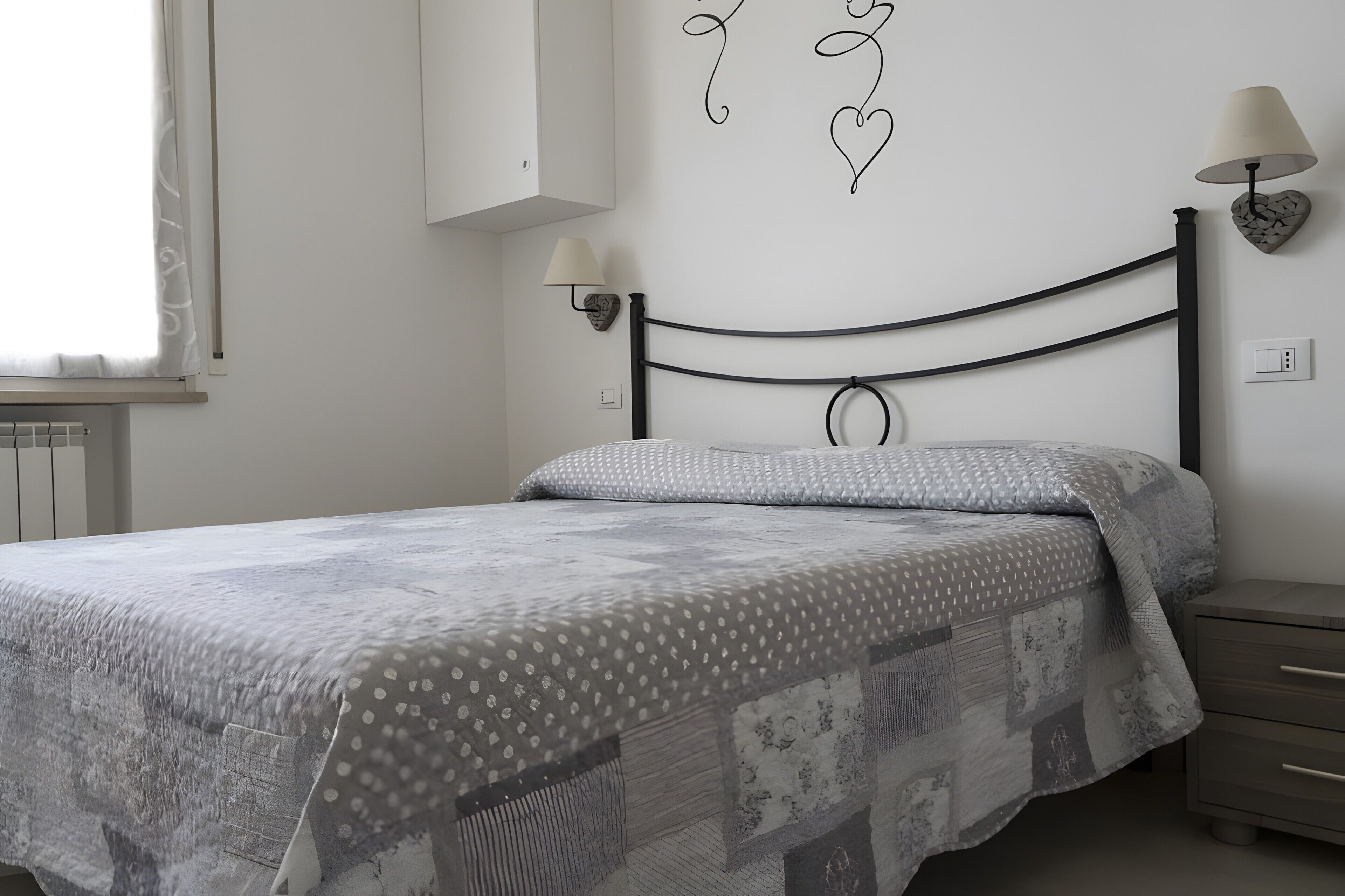 Ein Schlafzimmer mit einem Bett, Nachttischlampen, einer Wandleuchte und einer Heizung.