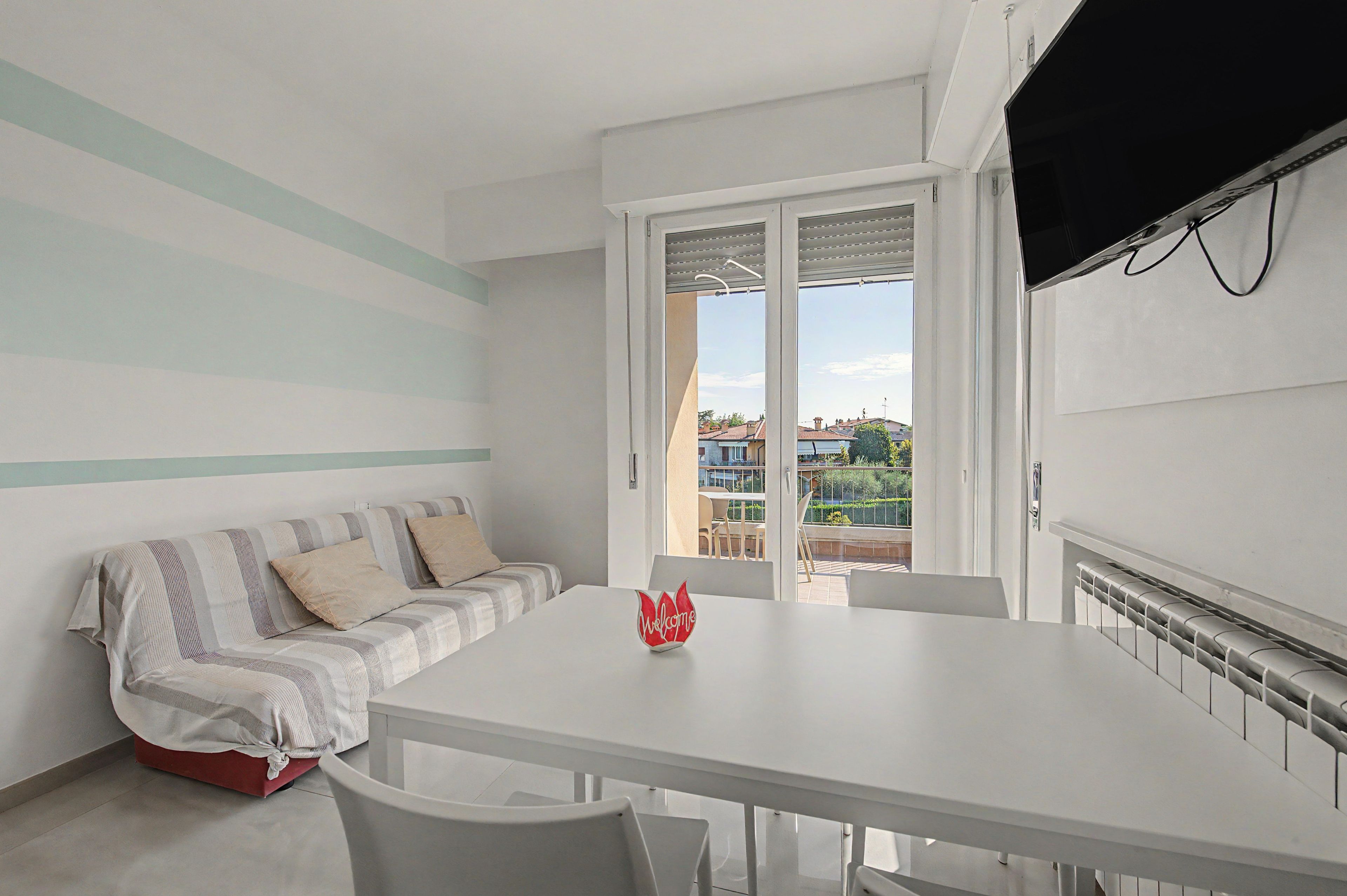 A modern living room with a sofa, a dining table, and a view of the outside.