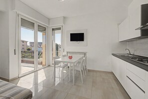 Eine moderne Küche mit Essbereich, einem an der Wand befestigten Fernseher und einem Balkon mit Blick auf die Umgebung.