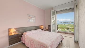 Ein Schlafzimmer mit einem Bett, Nachttischlampen, einem Gemälde und einem Balkon mit Blick.