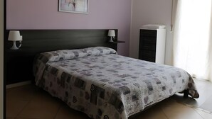Una camera da letto con un letto, due lampade da comodino, un comodino, una cassettiera e un quadro appeso al muro.