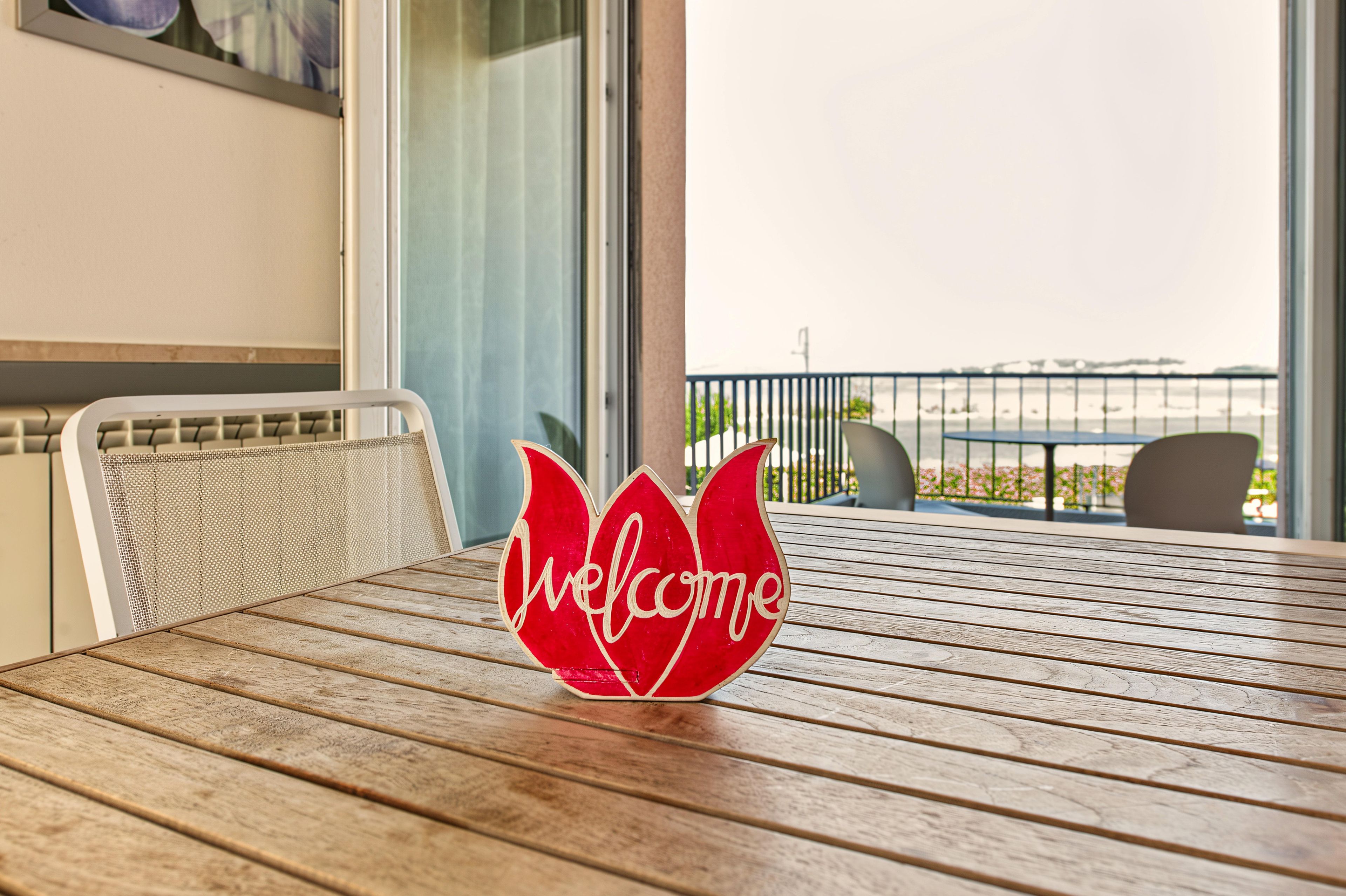 Ein Holztisch mit einem roten Schild, auf dem 'Welcome' steht.