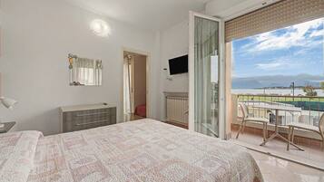 Un dormitorio con cama, cómoda, televisor y un balcón con vistas.
