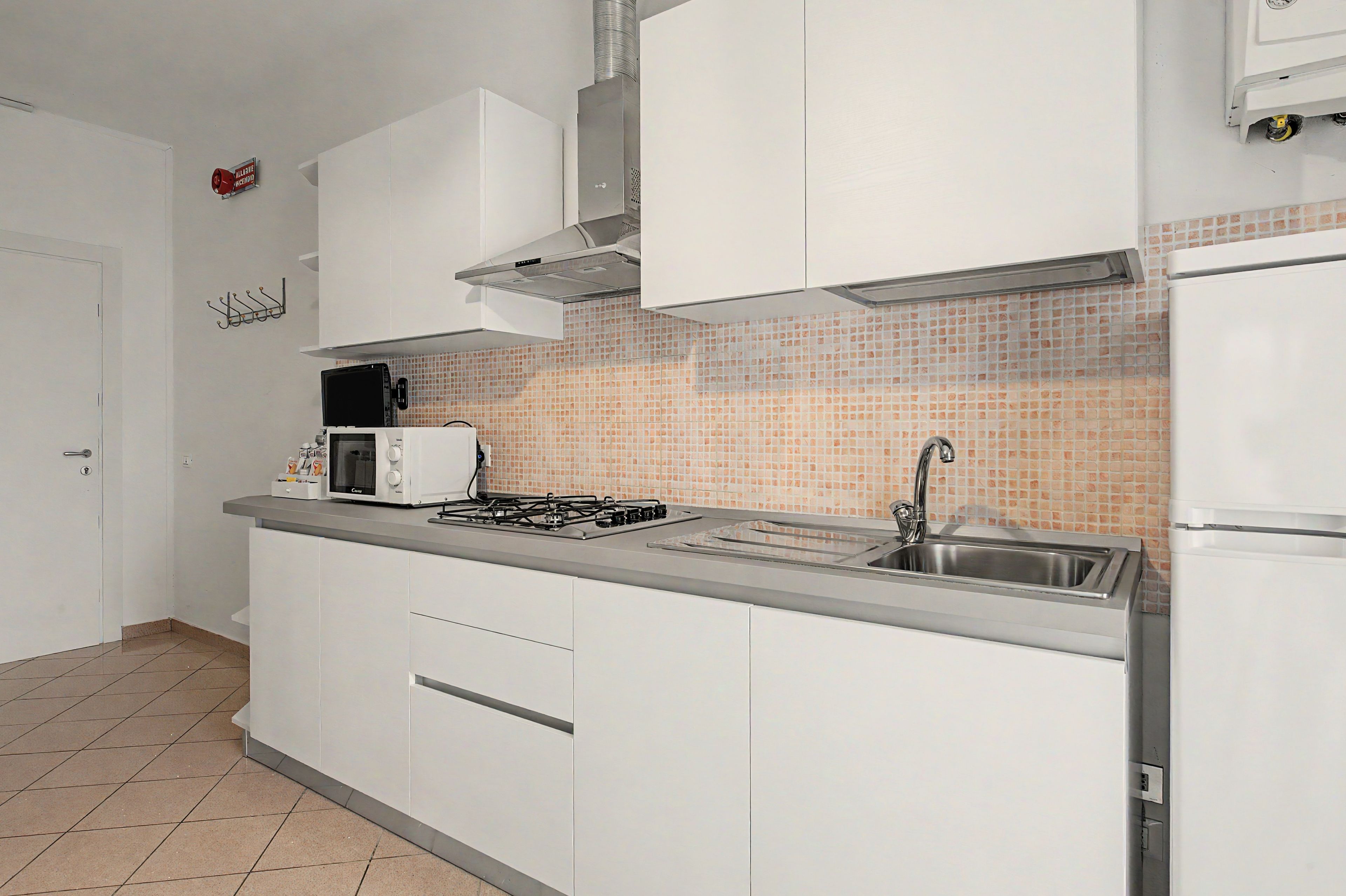 Une cuisine moderne avec des meubles blancs, une cuisinière à gaz, un four à micro-ondes et un évier en acier inoxydable.