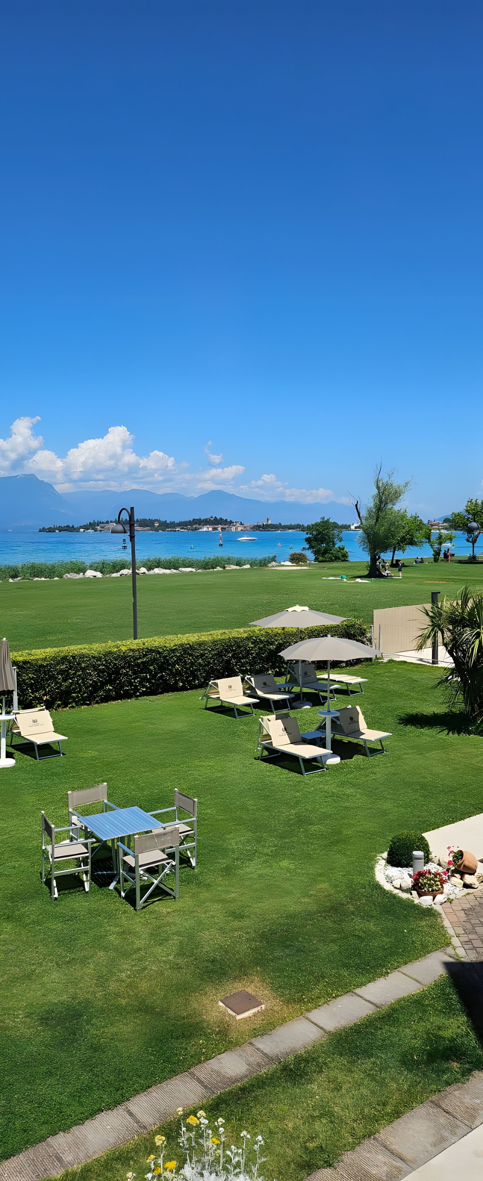 A well-maintained lawn with outdoor seating and a view of a body of water.