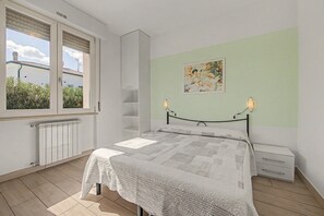 A bedroom with a bed, a radiator, a window with blinds, a wall-mounted shelf, and a painting. - 'Calla - Trilocale Deluxe' Apartment with Lake View, Wi-Fi and Air Conditioning (Sirmione)