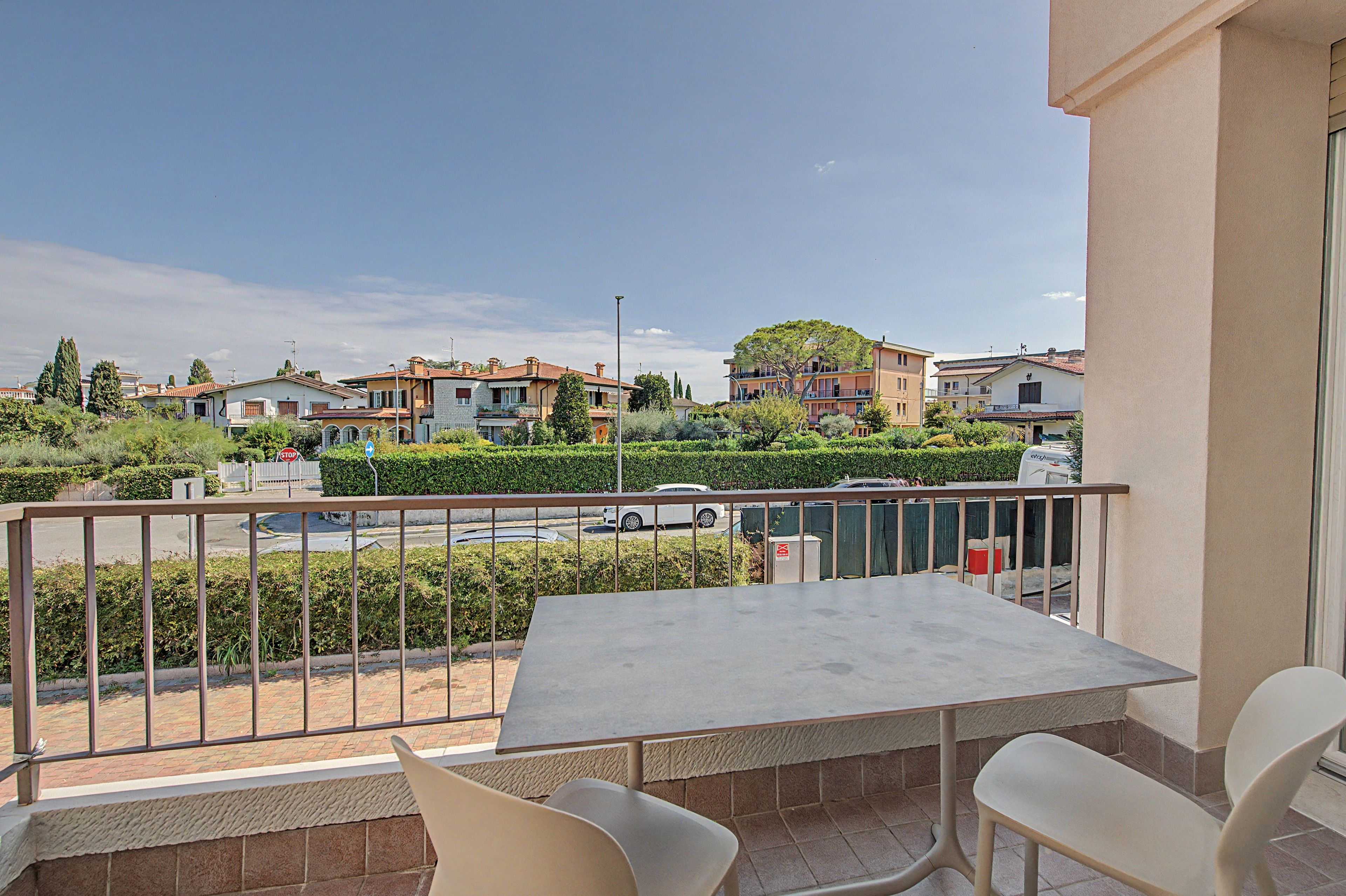 Ein Balkon mit Tisch und Stühlen mit Blick auf ein Wohngebiet mit Häusern und einer Straße.