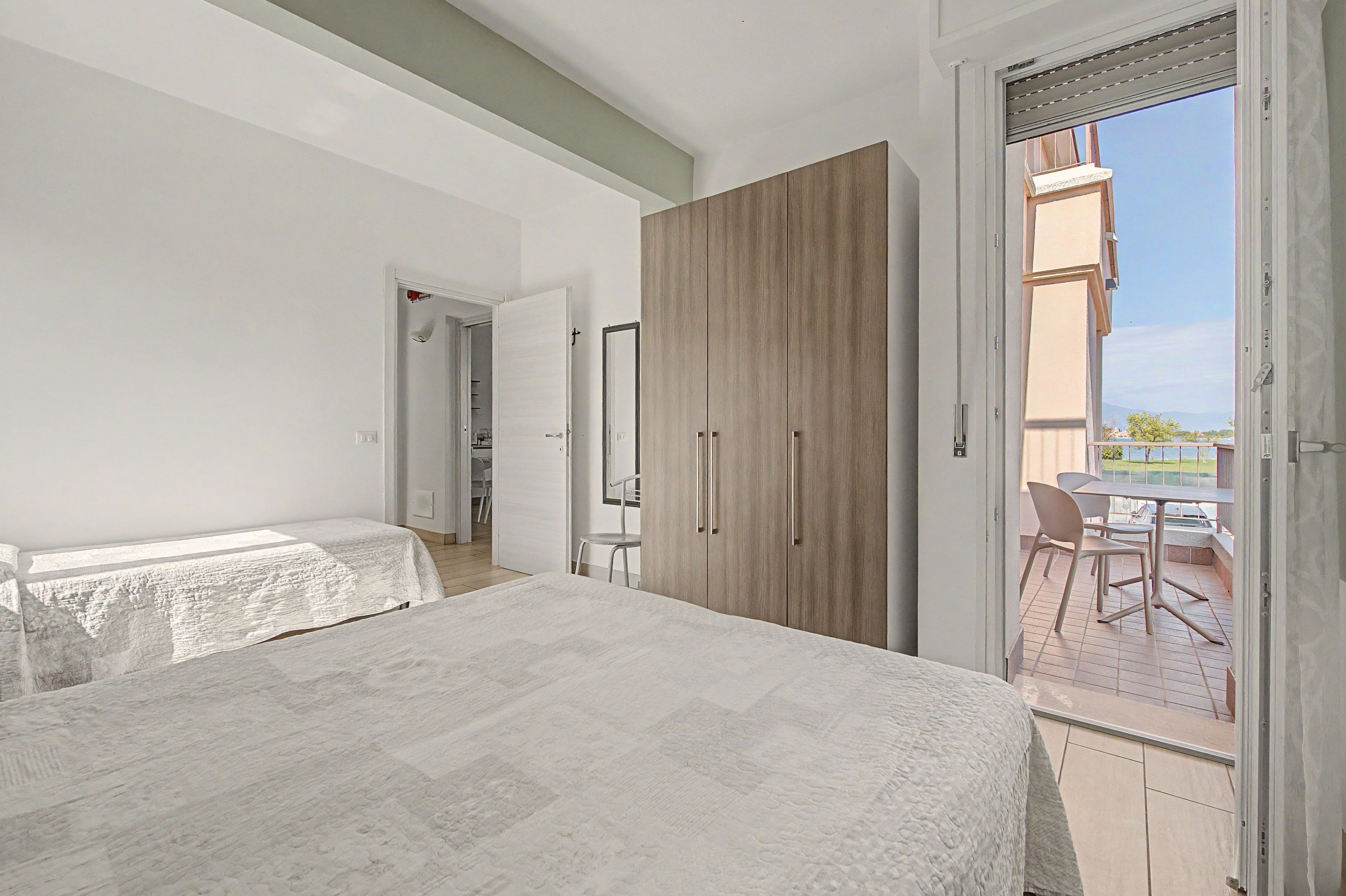 Une chambre à coucher comprenant un lit, une armoire et un balcon avec une table et des chaises.
