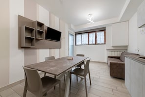 A modern kitchen with a built-in oven, a dining area with a table and chairs, and a living area with a sofa. - Ninfea Apartment – Superior Four-Room with Shared Pool, WiFi, and Air Conditioning (Sirmione)