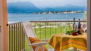 Ein Balkon mit Esstisch, der auf einen See mit Bergen im Hintergrund blickt.