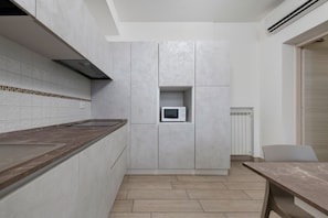 A modern kitchen with a built-in microwave, grey cabinets, and a wooden countertop. - Ninfea Apartment – Superior Four-Room with Shared Pool, WiFi, and Air Conditioning (Sirmione)
