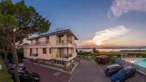 Ein mehrstöckiges Gebäude mit Balkonen, einem Swimmingpool und Blick auf den Sonnenuntergang über dem Wasser.