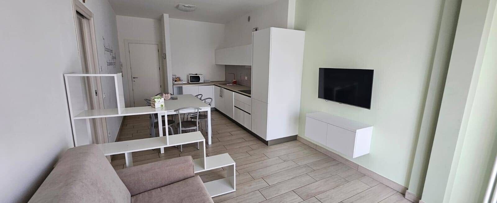Un apartamento moderno con comedor, kitchenette y televisor montado en la pared.