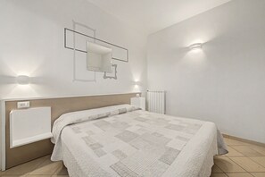 Een slaapkamer met een bed, een spiegel aan de muur en twee wandlampen.