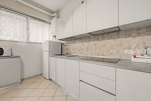 A modern kitchen with white cabinets, a stainless steel sink, and a tiled backsplash. - Ortensia Apartment - Economy Three-Room with Shared Pool, Wi-Fi, and Air Conditioning (Sirmione)