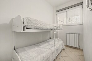 A bunk bed with a ladder, a window with curtains, and a radiator. - Ortensia Apartment - Economy Three-Room with Shared Pool, Wi-Fi, and Air Conditioning (Sirmione)